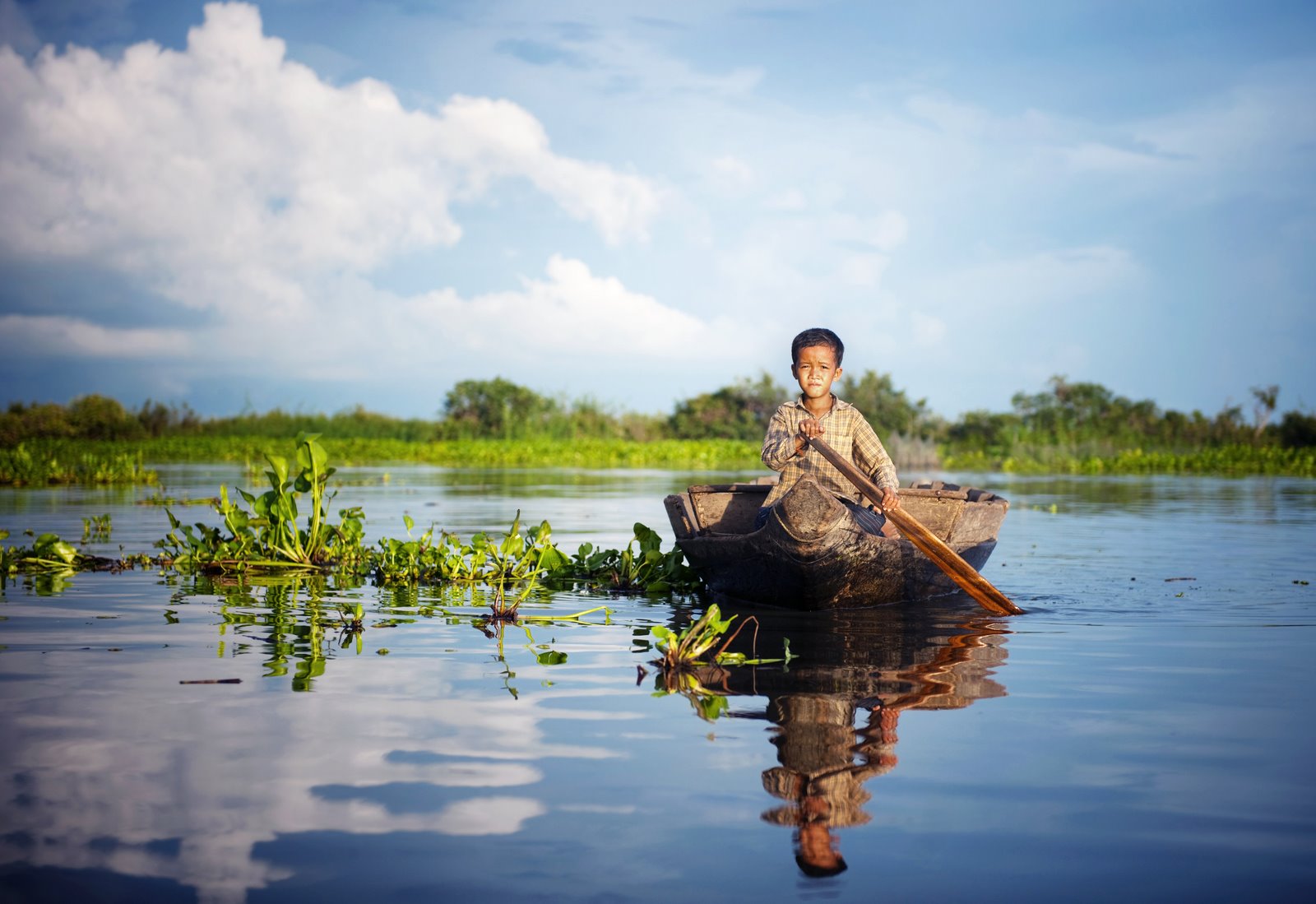 Cambodian boy traveling by boat in floating village